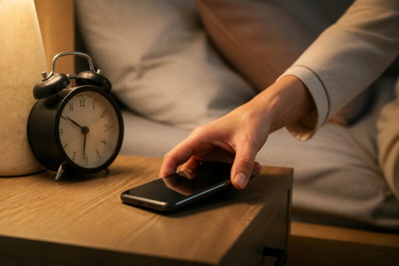 Abnehmen mit der richtigen Abendroutine: Hände legen ein Smartphone bewusst weg, symbolisch für Blaulicht-Detox als Teil einer gesunden Abendroutine.